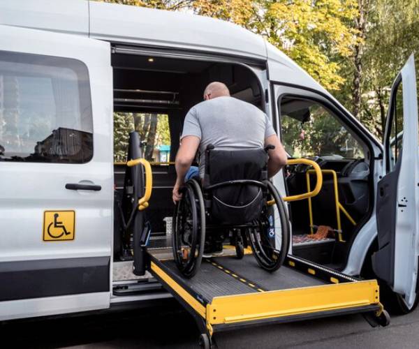 Wheelchair user boarding an accessible taxi van via side ramp