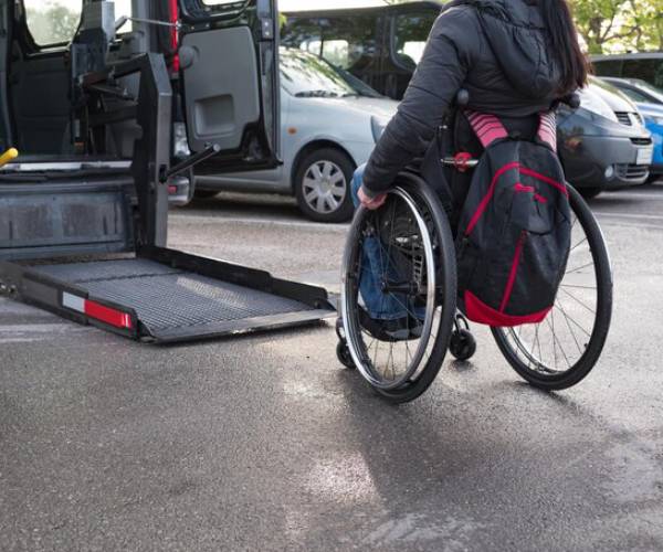 Wheelchair user approaching an accessible taxi van with ramp lowered