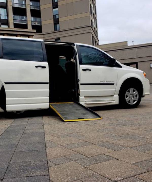 Wheelchair taxi van with access ramp lowered for safe passenger boarding